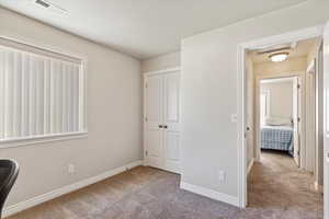 Unfurnished bedroom with a closet, visible vents, light carpet, and baseboards