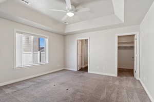 Unfurnished bedroom featuring baseboards, visible vents, a raised ceiling, light colored carpet, and a spacious closet