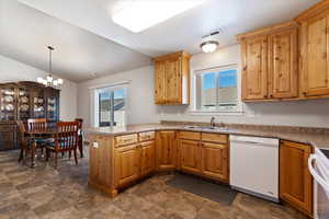 Kitchen with decorative light fixtures, white dishwasher, a sink, range, and a peninsula