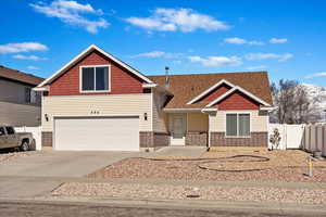 Traditional-style house with a garage, concrete driveway, and fence