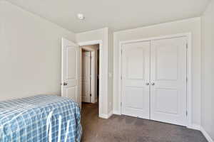 Bedroom with dark colored carpet, a closet, and baseboards