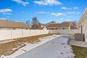 Yard layered in snow with a fenced backyard and a mountain view