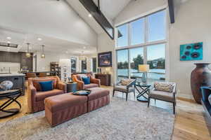 Living room featuring recessed lighting, light wood-style floors, high vaulted ceiling, beamed ceiling, and baseboards