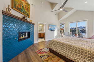 Bedroom with a fireplace, lofted ceiling, visible vents, wood finished floors, and baseboards