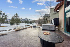 Snow covered patio with a mountain view and a fire pit