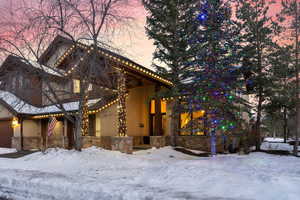 View of front of house featuring a garage, stone siding, and stucco siding