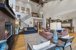 Living room featuring light wood-style floors, a tile fireplace, baseboards, and stairs