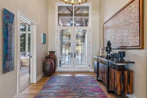 Entrance foyer featuring an inviting chandelier, french doors, baseboards, and wood finished floors