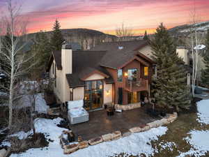 View of front of house featuring a balcony, a chimney, roof with shingles, a patio area, and a mountain view