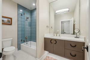 Full bath with bathing tub / shower combination, toilet, vanity, tile patterned flooring, and baseboards