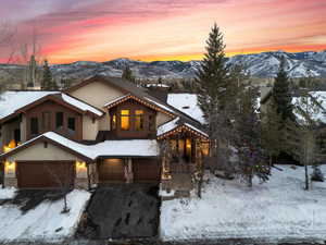 Rustic home featuring a garage, a mountain view, a chimney, and stucco siding