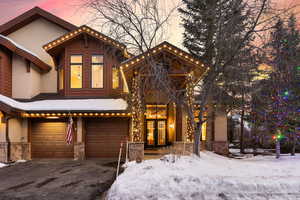 View of front of home with driveway, stone siding, a garage, and stucco siding