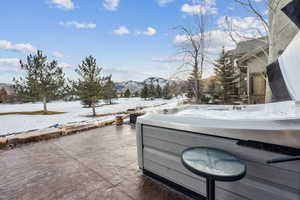 Snow covered patio with a hot tub and a mountain view