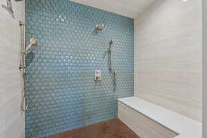 Bathroom featuring a tile shower and tile walls