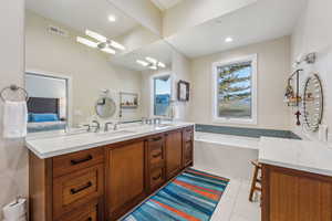 Bathroom with double vanity, visible vents, a tub, tile patterned floors, and a sink