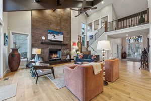 Living area with a fireplace, wood finished floors, visible vents, a towering ceiling, and french doors