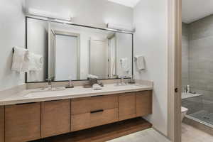 Full bathroom with double vanity, a sink, and toilet