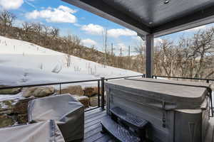 Snow covered deck with a hot tub and grilling area