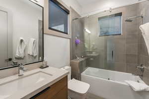 Full bath featuring toilet, bath / shower combo with glass door, and vanity