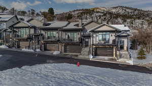 View of front facade featuring a garage, stone siding, a mountain view, and board and batten siding