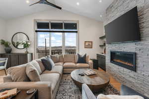 Living area with vaulted ceiling with beams, ceiling fan, recessed lighting, a fireplace, and light wood-style floors