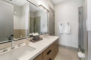 Bathroom with a stall shower, double vanity, a sink, and tile patterned floors