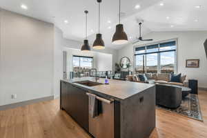 Kitchen featuring a kitchen island with sink, a sink, open floor plan, hanging light fixtures, and dishwasher