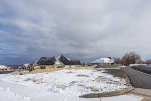 Yard covered in snow with a residential view and fence