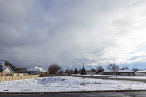 Yard layered in snow featuring fence and a residential view