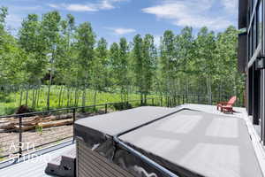 Wooden deck with a hot tub and view of scattered trees