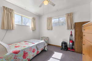 Bedroom featuring ceiling fan, multiple windows, and baseboards
