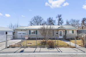 Ranch-style house featuring metal roof, concrete driveway, a fenced front yard, and a front yard