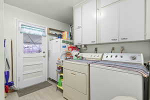Laundry room featuring light wood-type flooring, cabinet space, and washer and clothes dryer