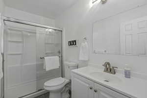 Full bath featuring a shower stall, toilet, and vanity