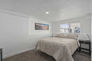 Carpeted bedroom with a paneled ceiling and baseboards