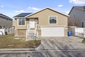 View of front facade featuring stone siding, fence, and stucco siding