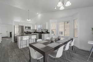 Dining space featuring lofted ceiling, baseboards, dark wood finished floors, and an inviting chandelier