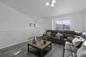 Living room with a chandelier, recessed lighting, wood finished floors, baseboards, and vaulted ceiling