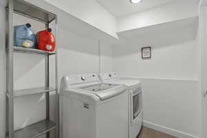 Clothes washing area featuring laundry area, baseboards, and washer and clothes dryer