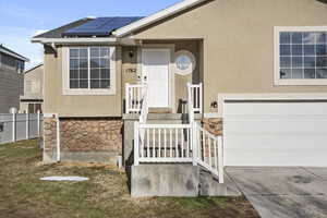 Property entrance featuring stucco siding, fence, and solar panels