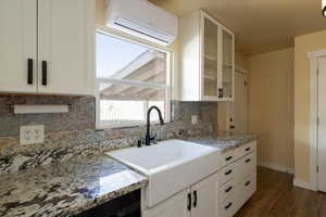 Kitchen with porcelain farmhouse sink, granite counters, and a mini split ductless air conditioning unit