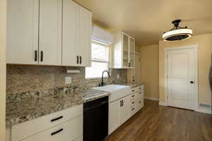 Kitchen with a sink, white cabinets, hanging light fixtures, dishwasher, and glass insert cabinets side door to carport and laundry closet