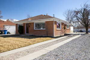 View of front of house with a front yard, brick siding, and the rv pad and west driveway