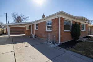 View of front of home featuring concrete east driveway, an attached carport and almost the garage.