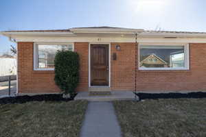 Property entrance with a yard and brick siding