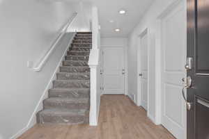 Entryway featuring baseboards, visible vents, stairway, and wood finished floors