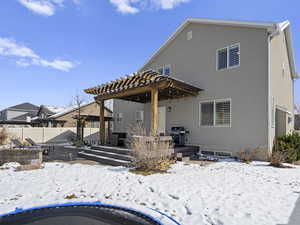 Snow covered property with fence, a pergola, and stucco siding