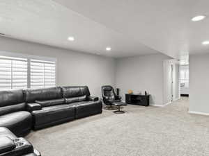 Carpeted living area with recessed lighting, visible vents, and baseboards