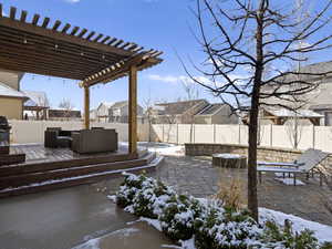 Snowy yard with a fenced backyard, a residential view, a pergola, and a patio