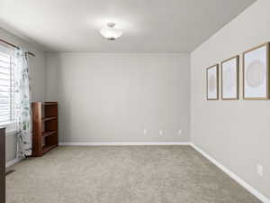 Spare room featuring light colored carpet and baseboards